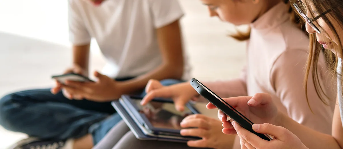 tres niños de la generación alpha usando dispositivos digitales